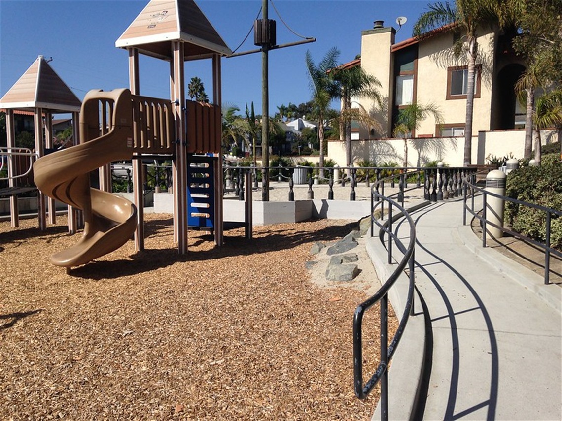 Pirate-themed playground with spiral slide, climbing steps, and palm trees in the background.