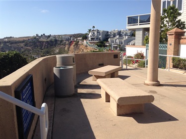 Bluff top trail's concrete benches on a curved patio with ocean view and houses in the background