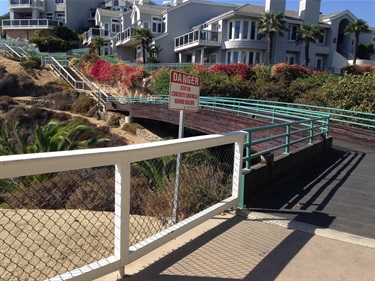 Bluff Top Trail's pedestrian walkway with railings leading uphill toward houses, with a warning sign reading ‘Danger