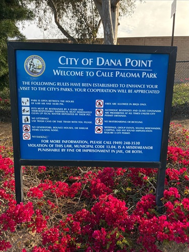 City of Dana Point park rules sign at Calle Paloma Parkette surrounded by colorful flowering landscaping.
