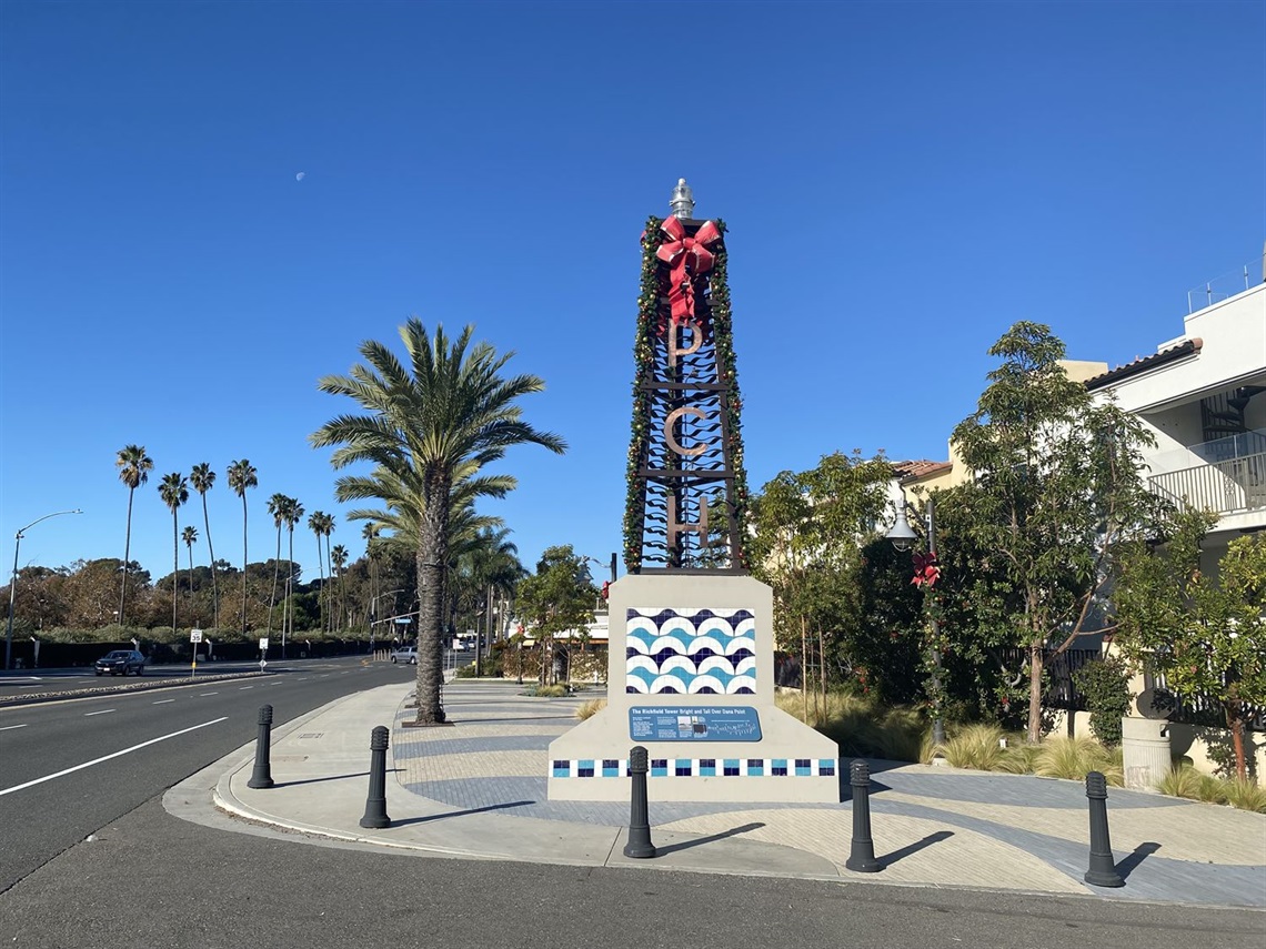 Wide view of the PCH sign decorated for the holidays with garland, lights, and a large red bow.